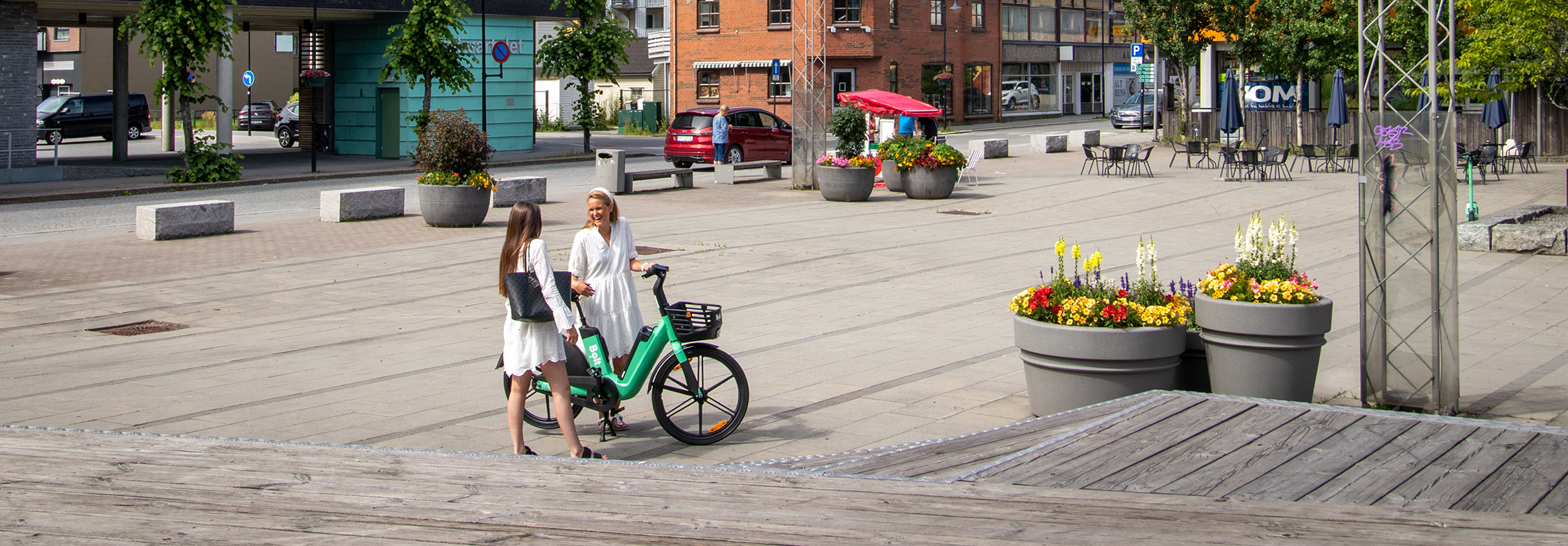 Bildet viser to damer og en sykkel på torget i mjøndalen