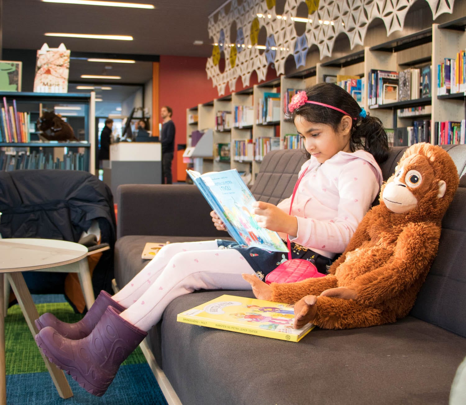 jente som leser bok i en sofa på det nye biblioteket på Fjell