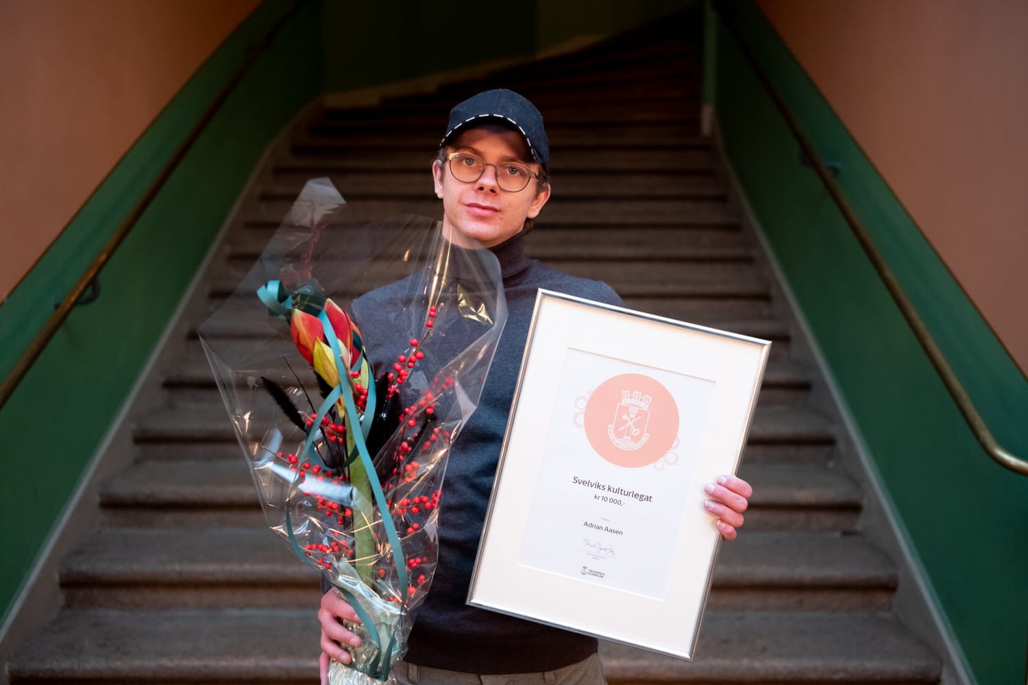 Adrian Aasen holder opp blomst og diplom.