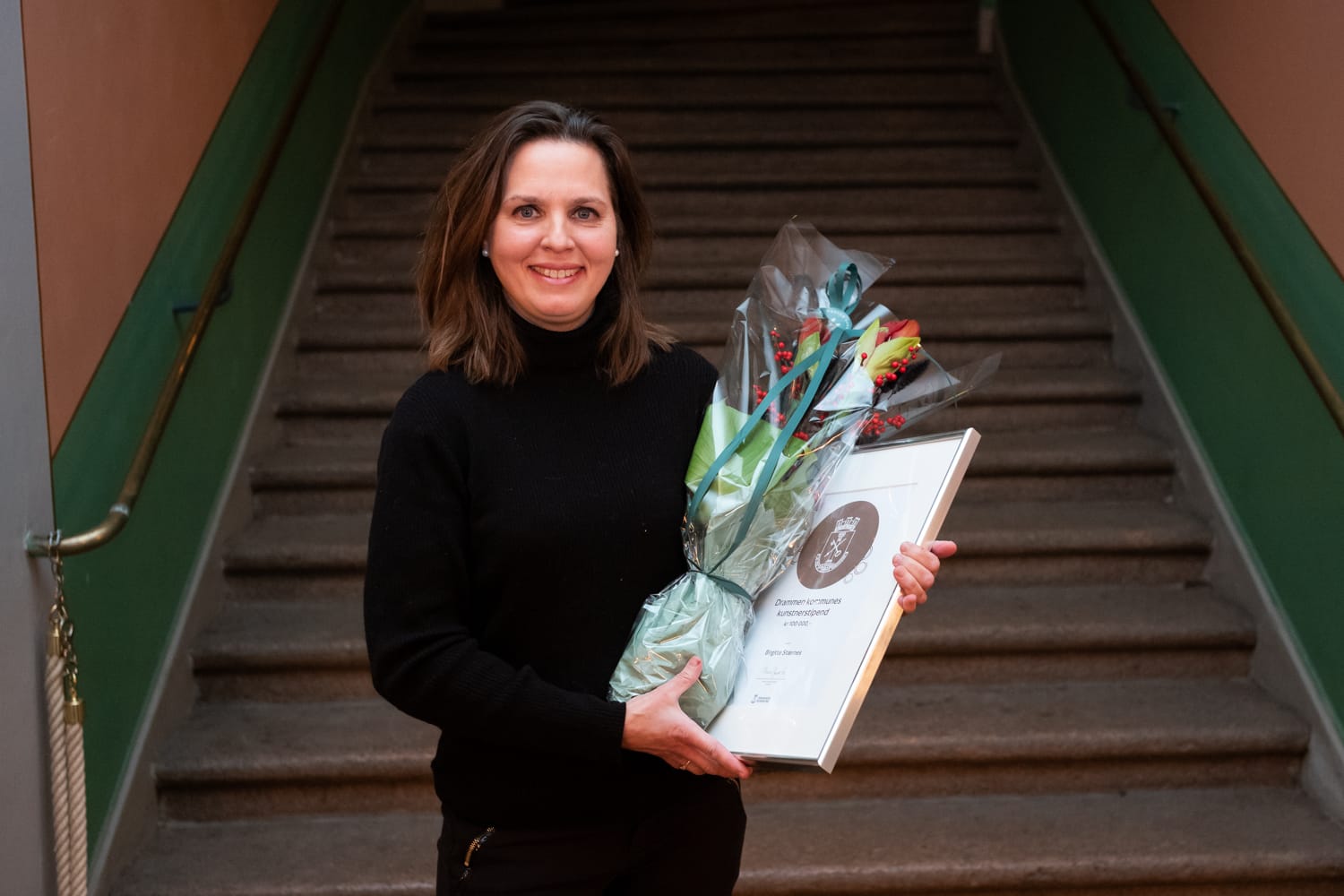 Birgitte Strærnes med diplom og blomst i hånda. 