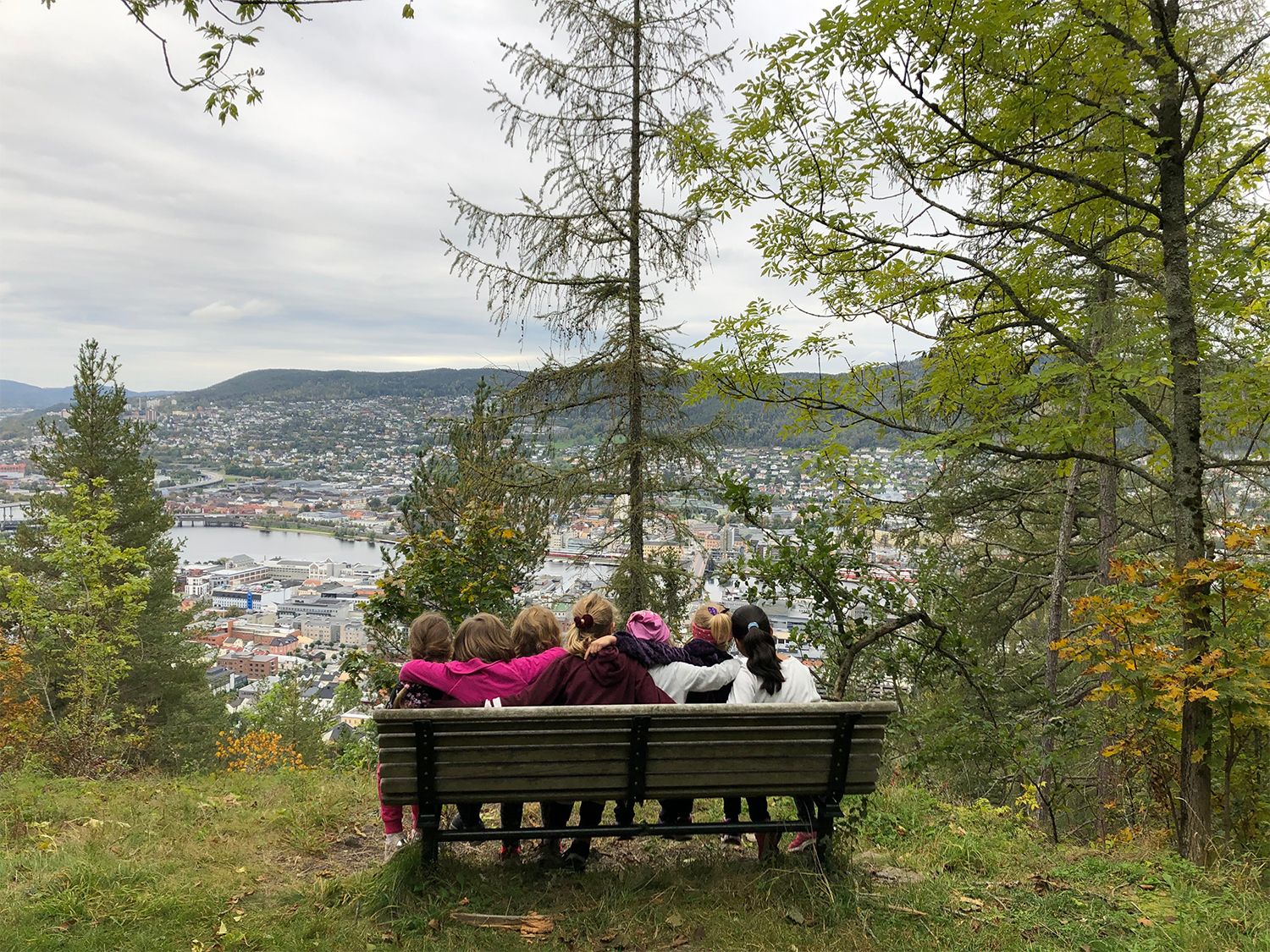 barn sitter på en krakk og ser utover byen. I skogen, grønn natur