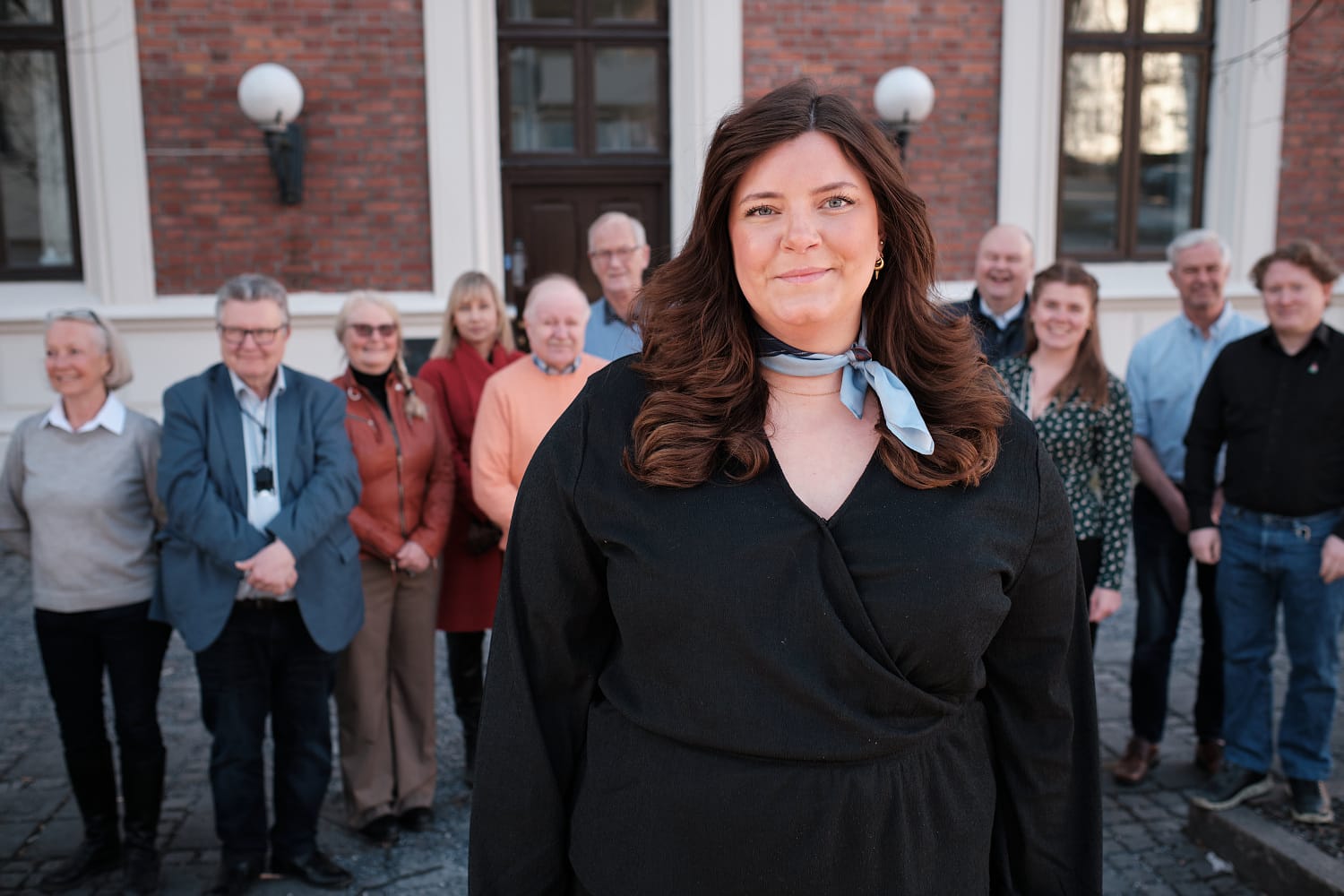 Leder Lina Strandbråten står foran de andre medlemmene i hovedutvalget utenfor rådhuset.