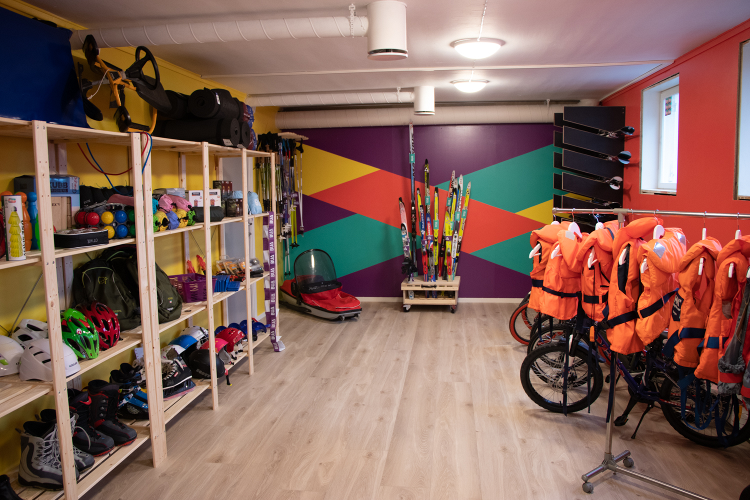 Et nytt fargerikt lokale med fritidsutstyr som redningsvester, sykler og ski.