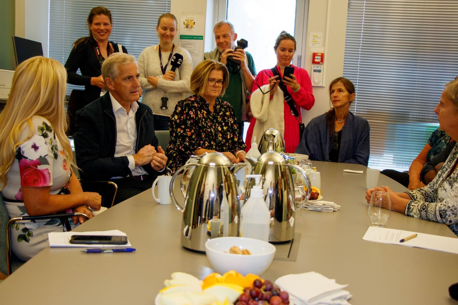 Jonas Gahr Støre, Monica Myrvold Berg og ansatte fra Ungdomstorget rundt bordet på et møterom.