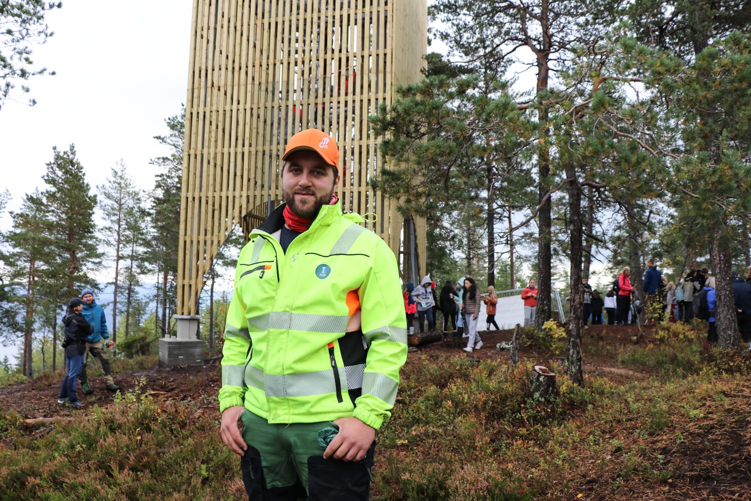Byggeleder i Drammen kommune med gul arbeidsjakke foran et nytt utsiktstårn i tre i marka.