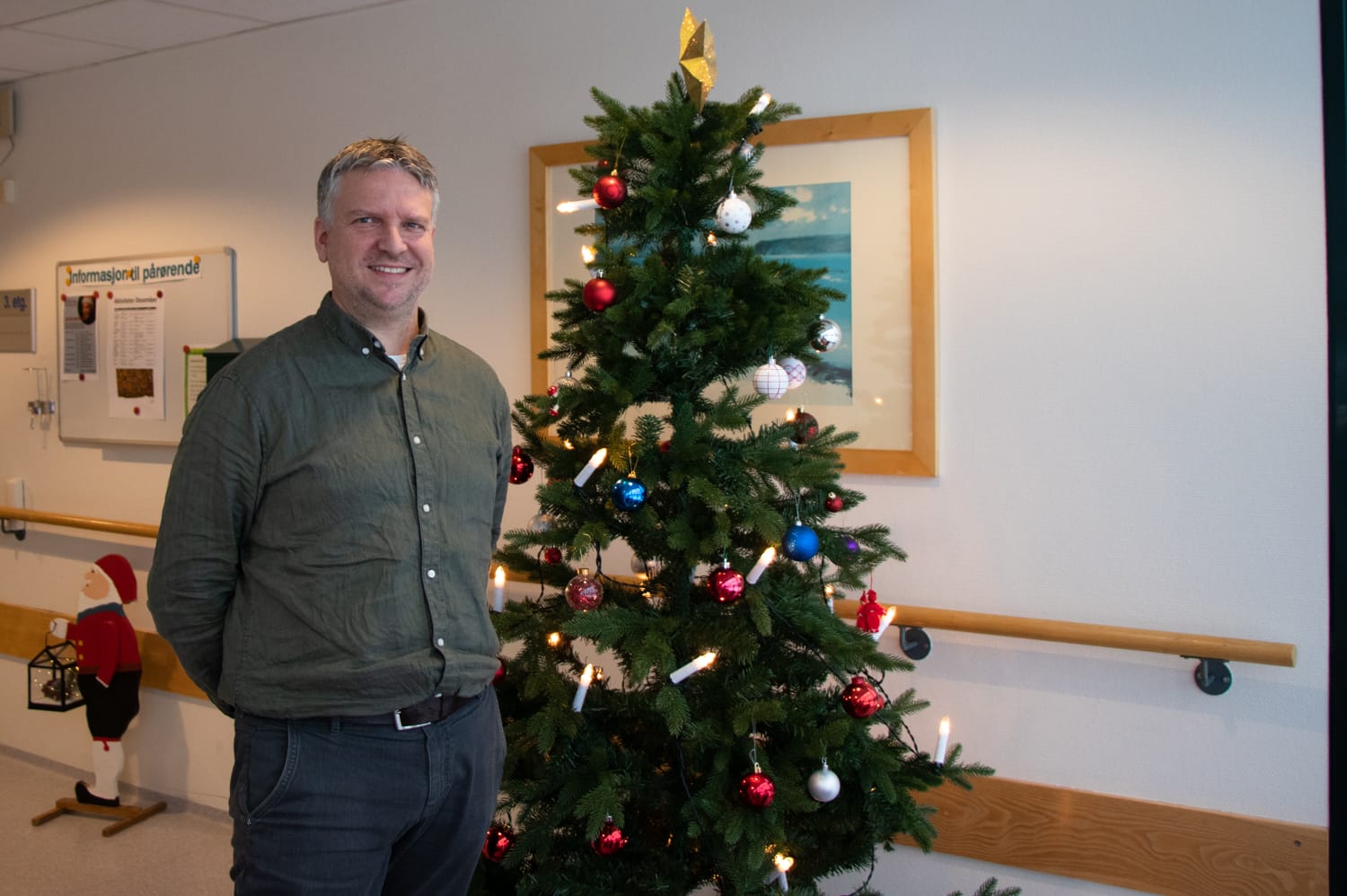 Avdelingsleder TRond Smemo står smilende foran et juletre på Losjeplassen.