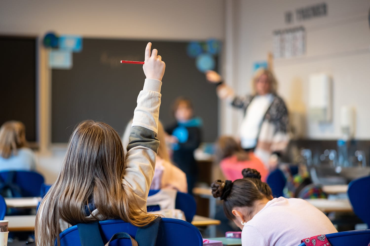 En elev rekker opp hånden i et klasserom. 