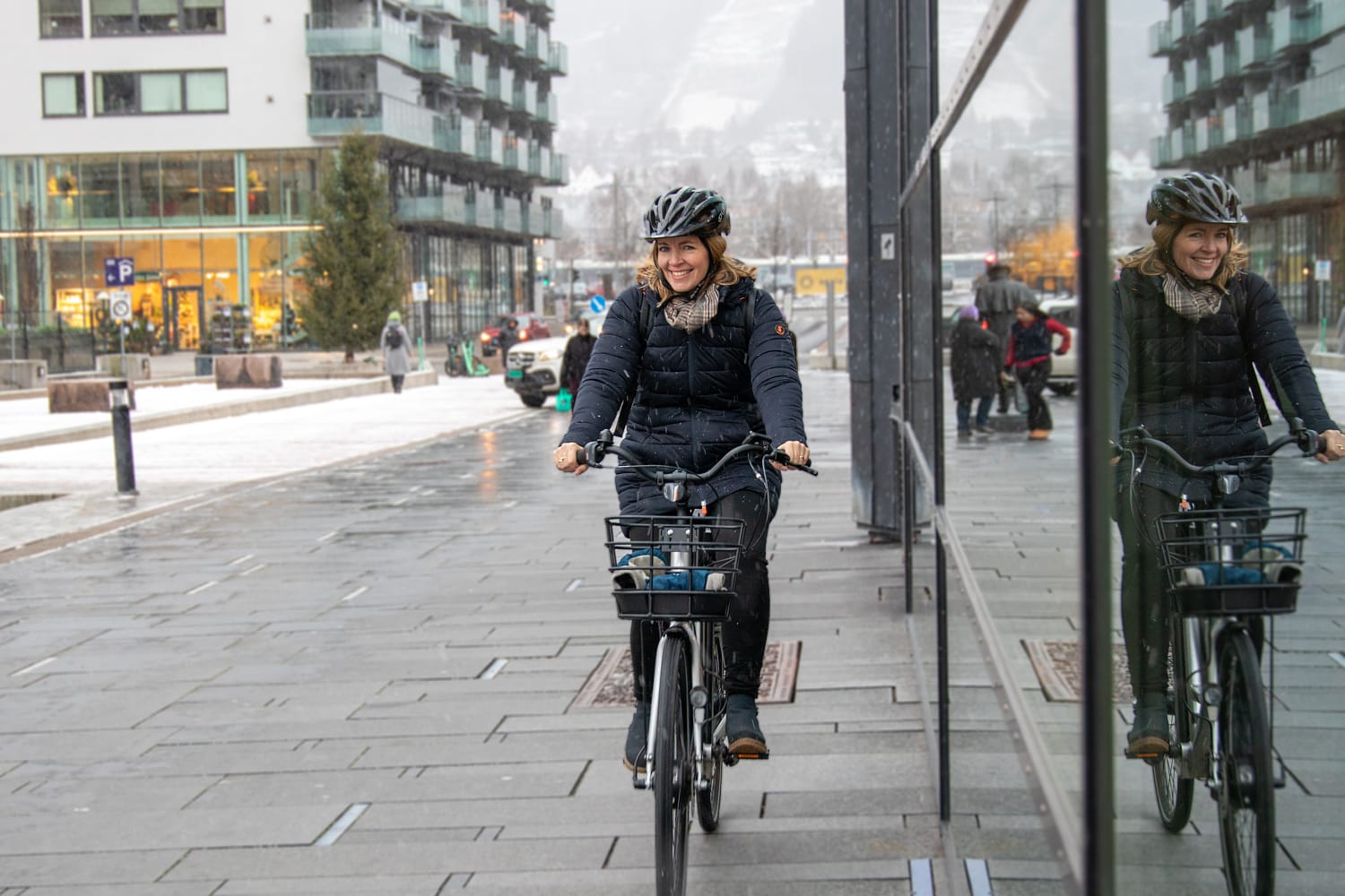 Ung kvinne på sykkel om vinteren i sentrumsområde