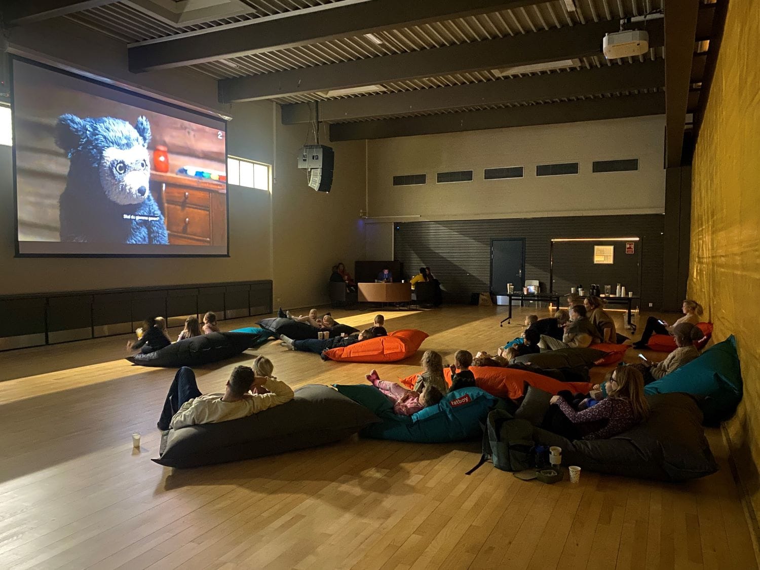 Barn ligger på sakkosekker i gynsalen på KNutepunkt Strømsø og ser på film