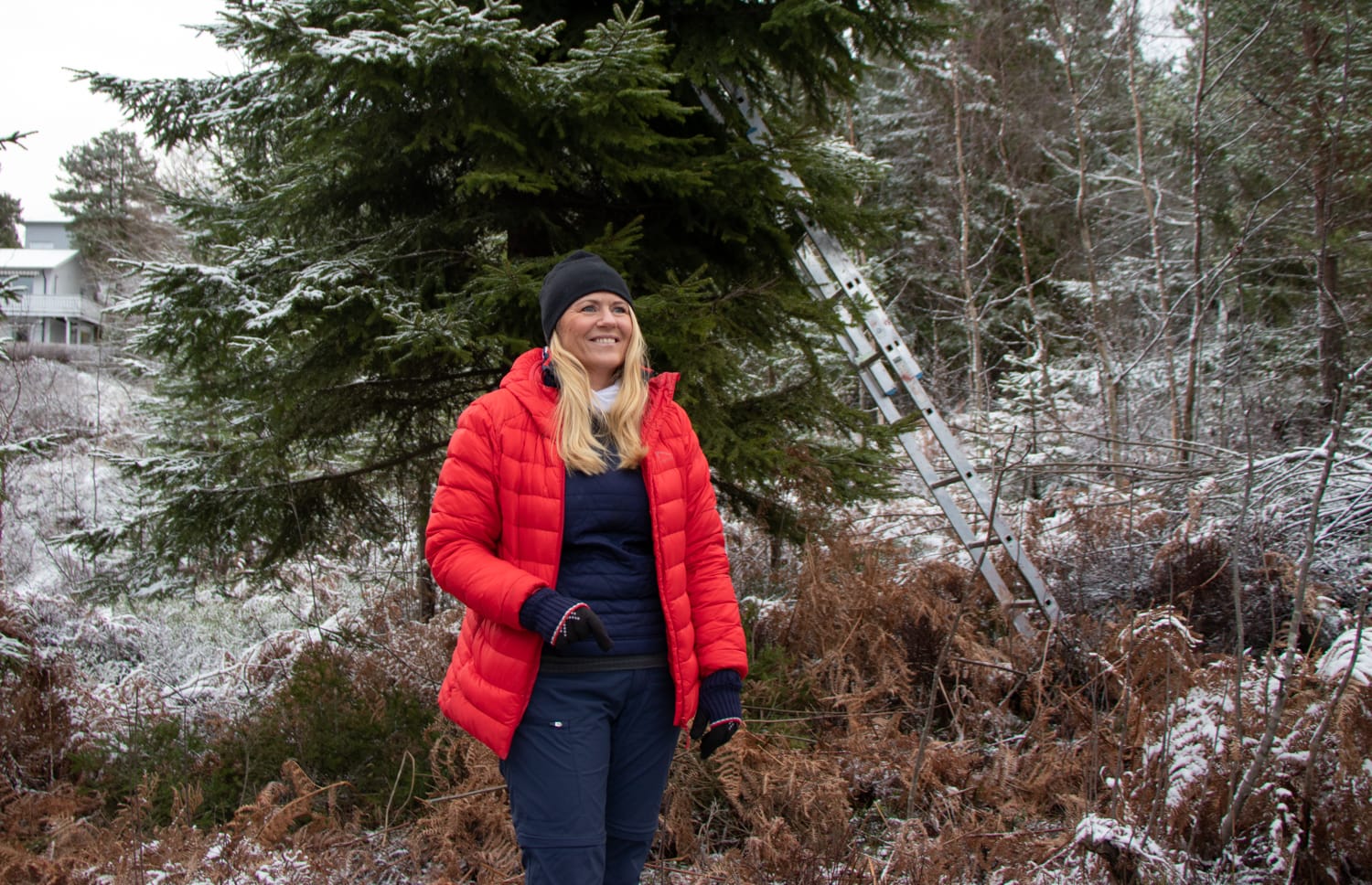 Ordfører står i skogen på Konnerud og smiler foran et juletre som skal til Kiel.