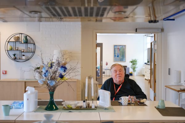 En eldre mann sitter ved et bord og spiser mat. Bordet er pyntet.