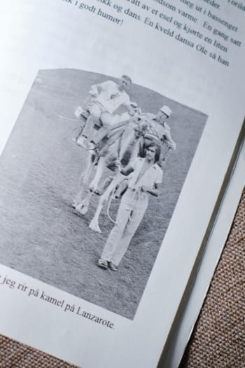 Et sort-hvitt bilde av en ung gutt på ryggen til en kamel. 