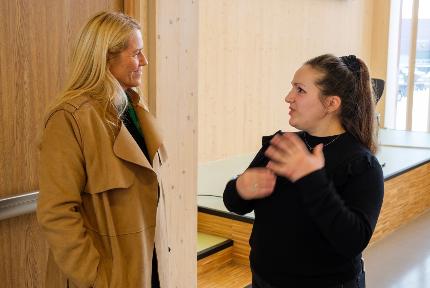 anna i sort genser prater med Monica Myrvold Berg som har på seg en beige kåpe