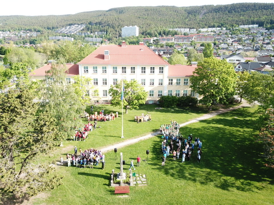 dronebilde av Åssiden skole med elever kledd i regnbuens farger