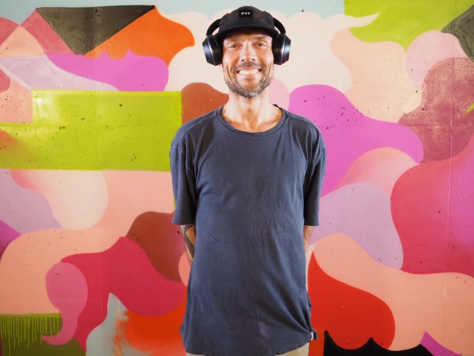 an mann med hodetelefoner foran en fargerik vegg