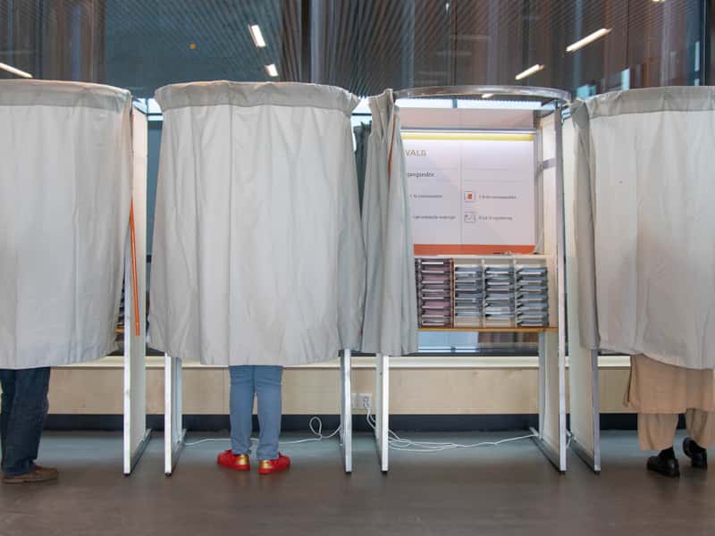 Fire valgavlukker med tre mennesker  bak forheng