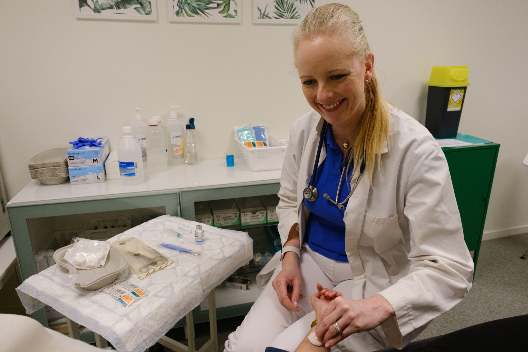 En kvinnelig lege i hvite legeklær holder en pasients hånd i sin hånd.