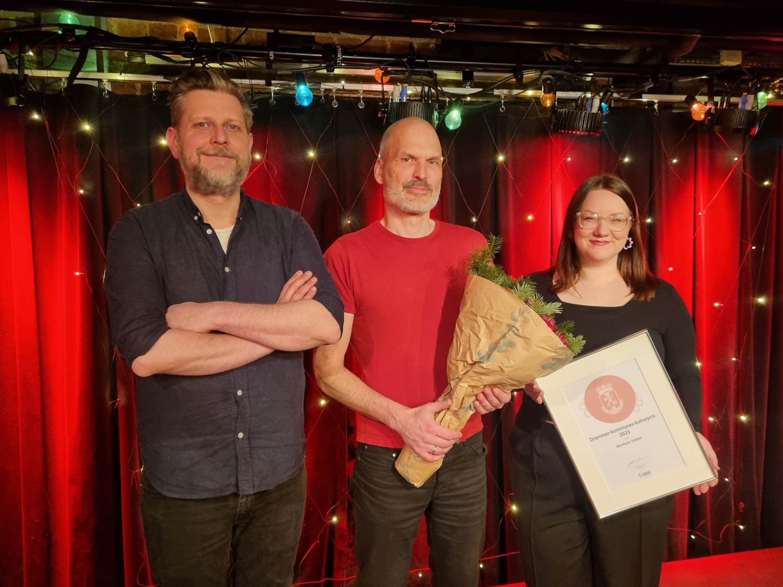 Frode Bjørnstad, Rune Valle Tangen og Marit Stokkenes på scenen og viser fram diplomet for kulturprisen 2023