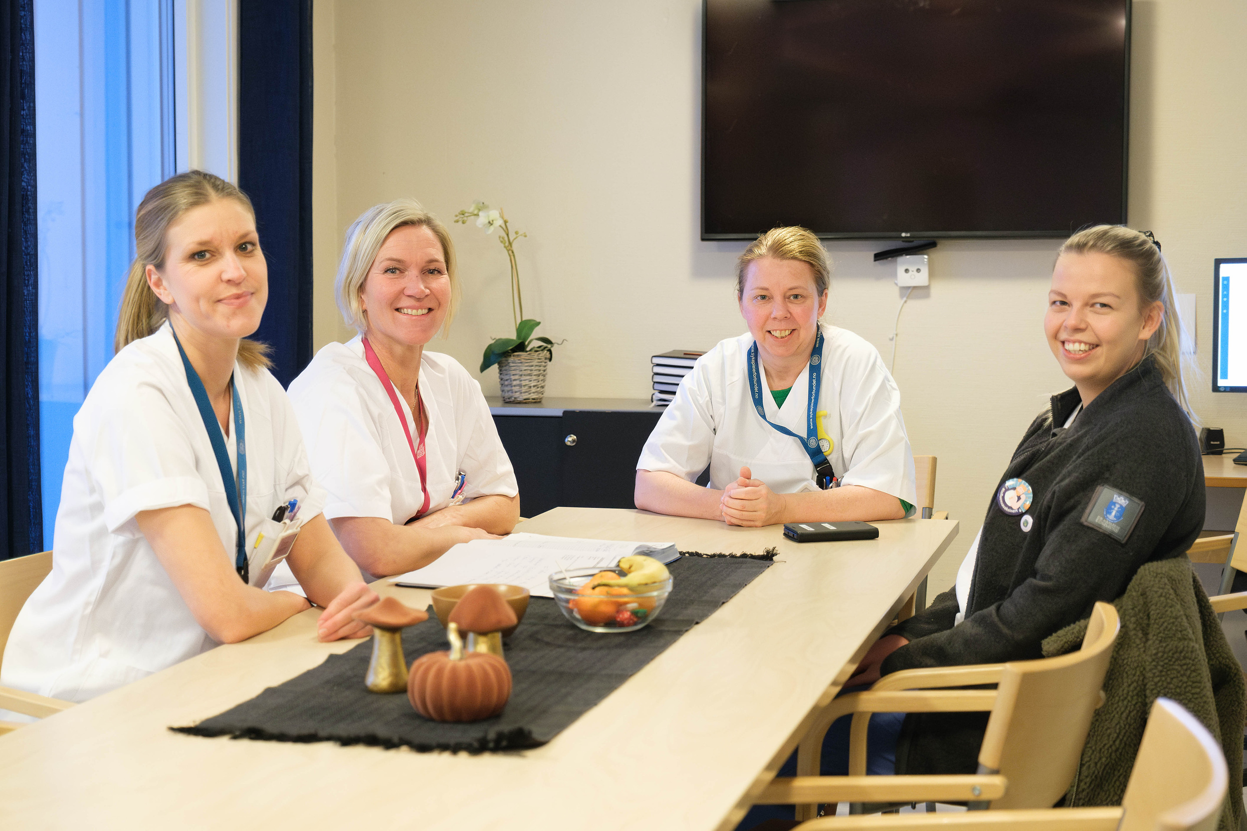 Fire sykepleiere som sitter rundt et bord på et møterom