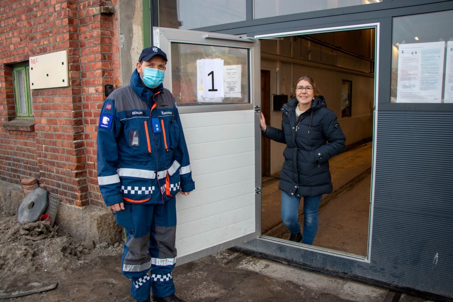 En fra sivilforsvaret står sammen med Liv Mikkelborg i døra inn til teststasjonen.