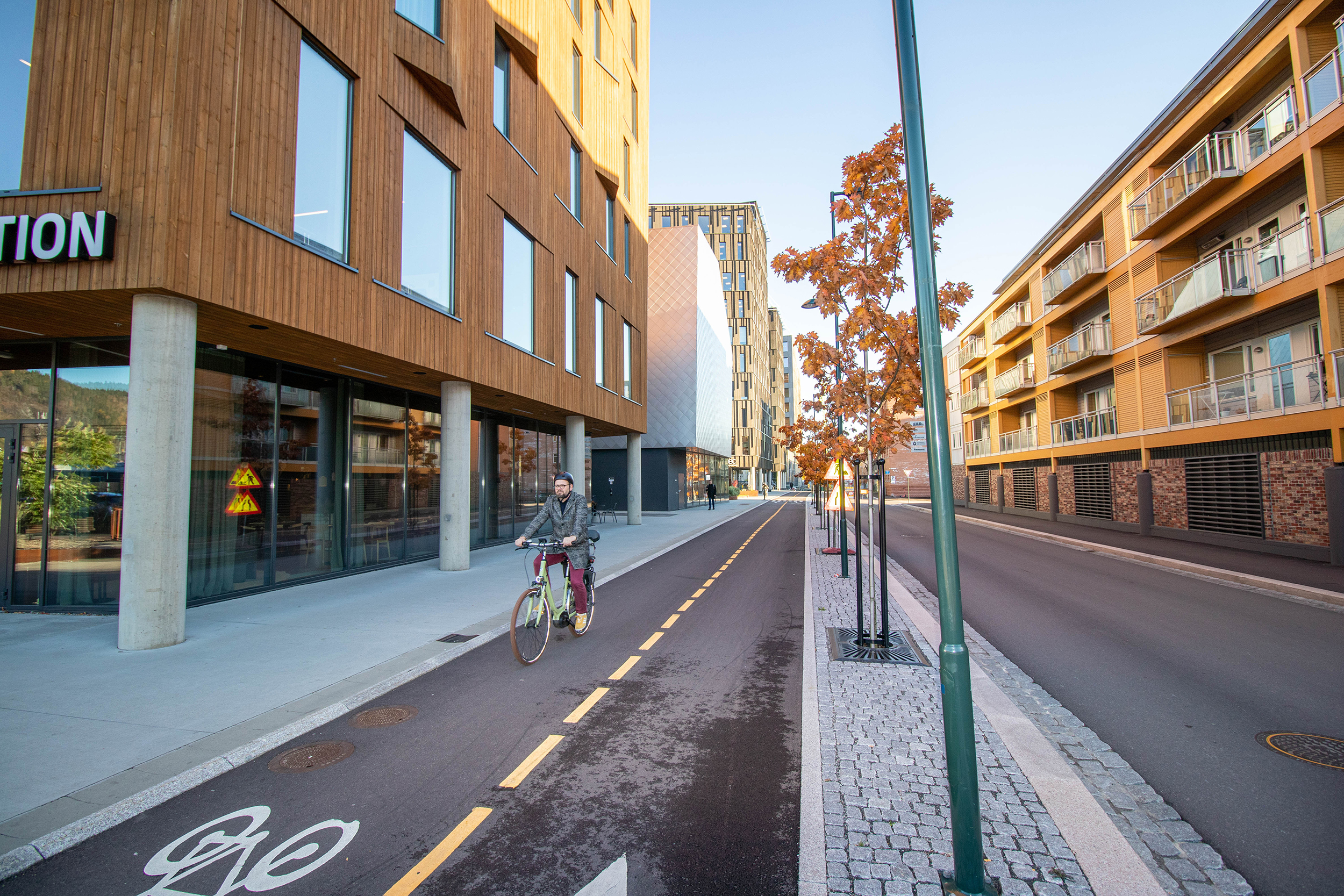 Person på sykkel på sykkelvei mellom urban bebyggelse.