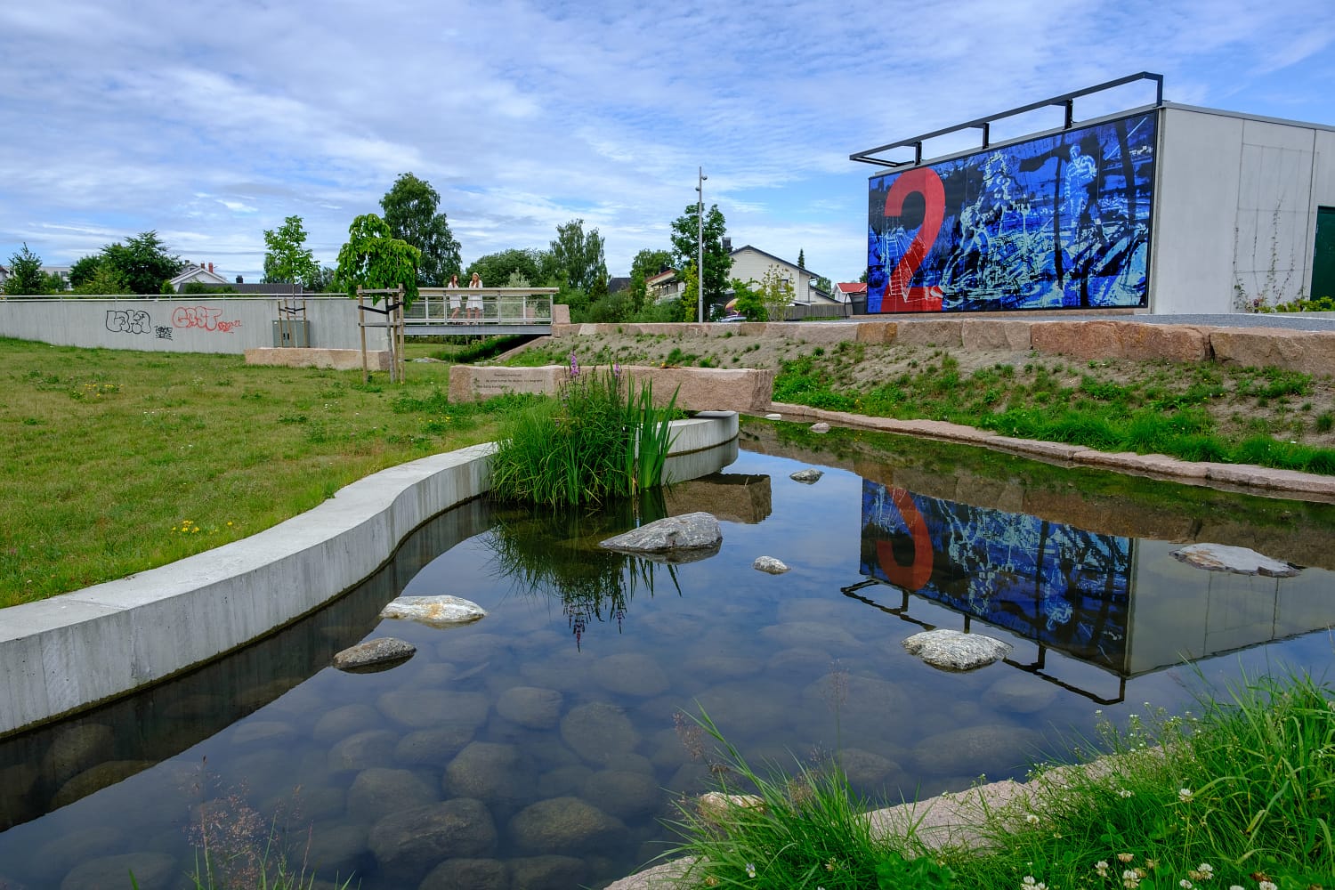 Wildenveys plass. Park med granitmur, vannspeil og glasskunst.