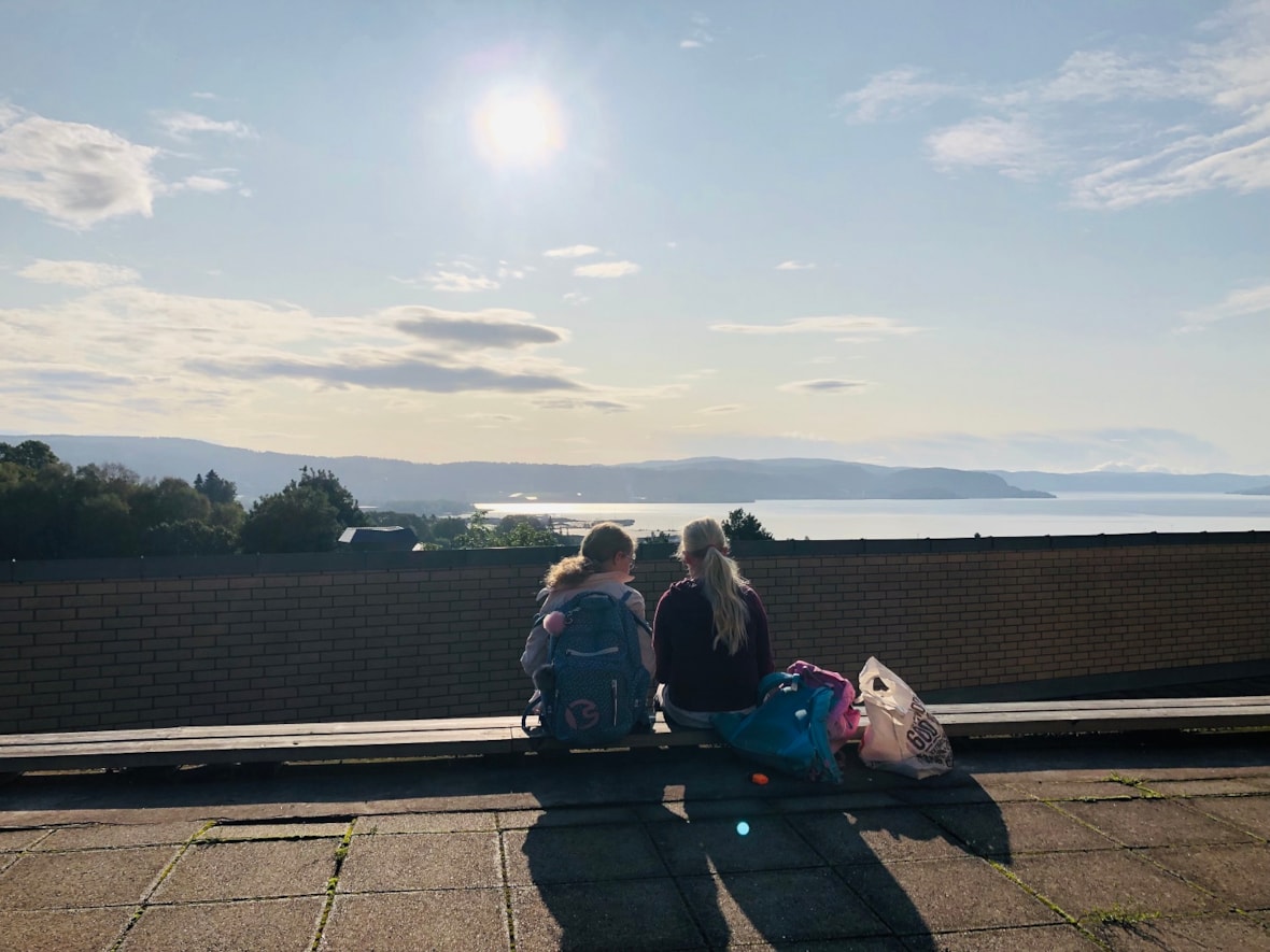 To elever sitter i skolegården og ser ut over Drammensfjorden