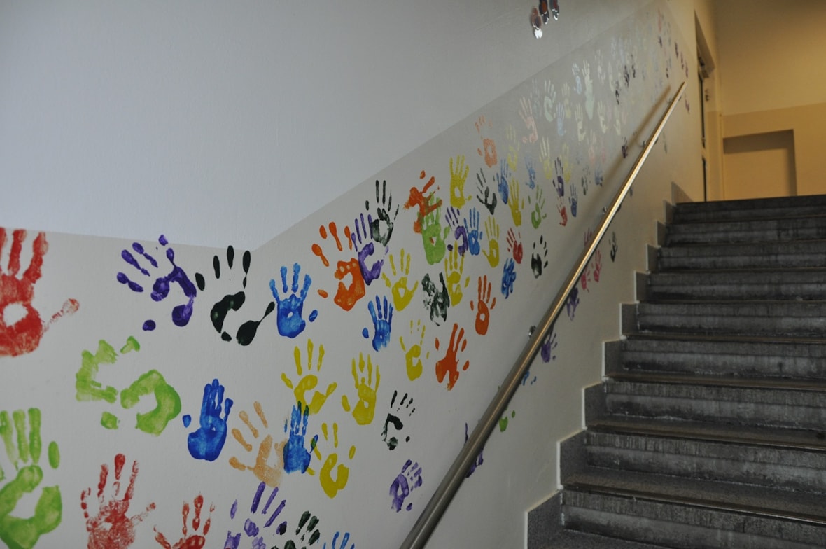 Avtrykk av alle hendene til elevene på veggen ved trappa