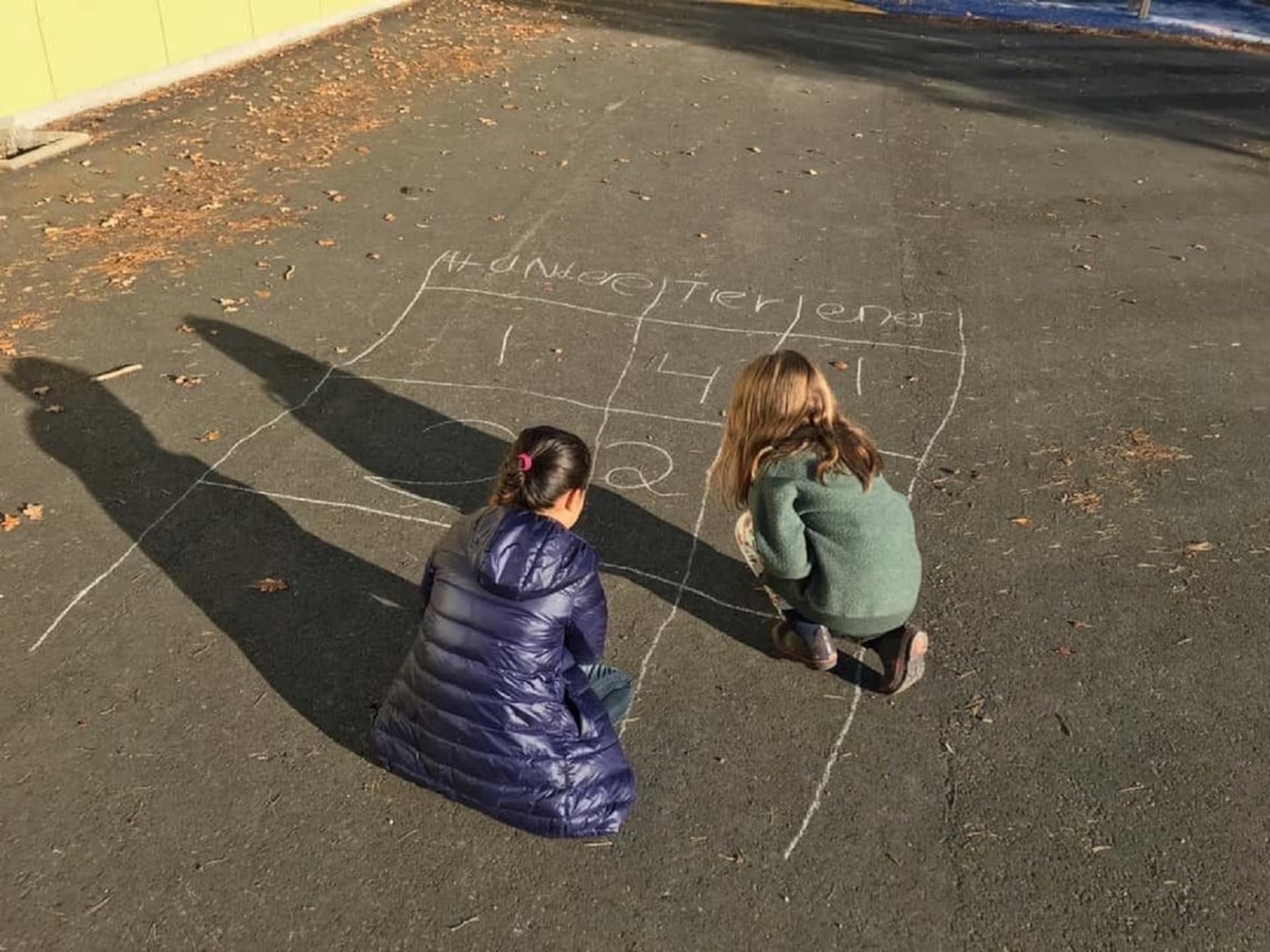 To elever tegner tall på asfalten.