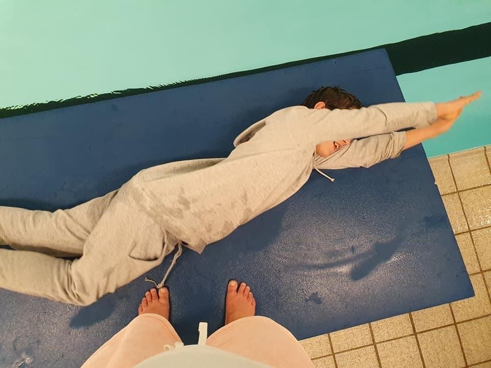 Et bilde som viser at en elev øver på å rulle ut i vannet i svømmehallen